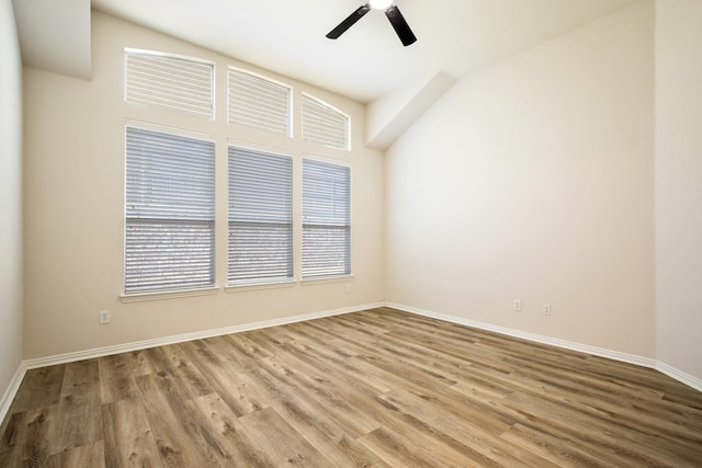 spare room with wood finished floors, a ceiling fan, and baseboards