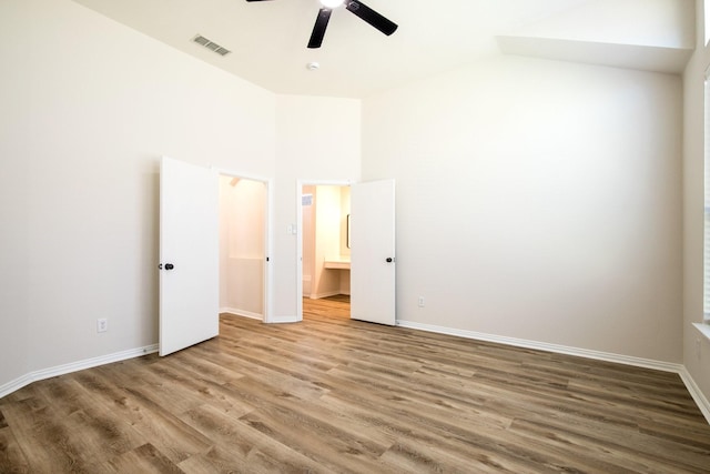 unfurnished bedroom featuring vaulted ceiling, visible vents, baseboards, and wood finished floors