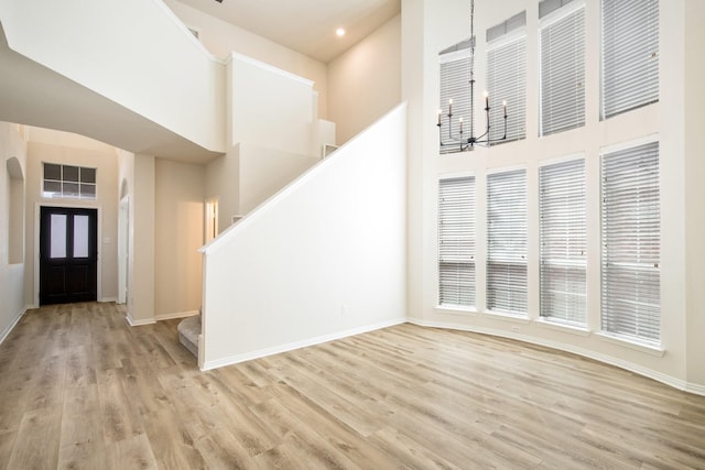 foyer with stairs, wood finished floors, a towering ceiling, baseboards, and recessed lighting