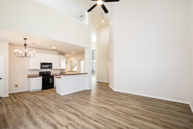 kitchen with ceiling fan with notable chandelier, open floor plan, light wood-style flooring, and black appliances