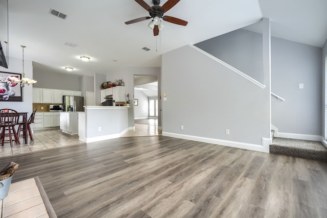 unfurnished living room featuring visible vents, a ceiling fan, light wood-style floors, and stairway