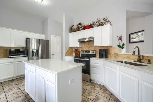 kitchen featuring tasteful backsplash, stainless steel appliances, under cabinet range hood, a kitchen island, and a sink