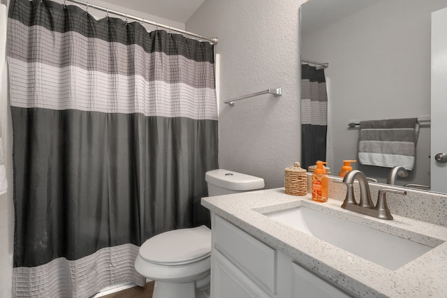 full bathroom featuring toilet, a shower with curtain, a textured wall, and vanity