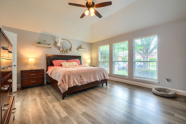 bedroom featuring light wood finished floors, ceiling fan, vaulted ceiling, and baseboards