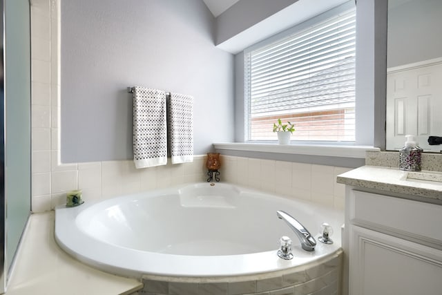 full bathroom with a wealth of natural light, a garden tub, and vanity