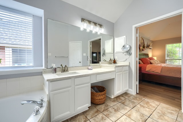 full bathroom with connected bathroom, tile patterned flooring, vaulted ceiling, a bath, and vanity
