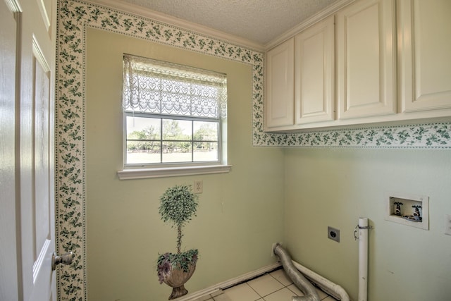 washroom featuring a textured ceiling, hookup for an electric dryer, ornamental molding, cabinet space, and light tile patterned floors