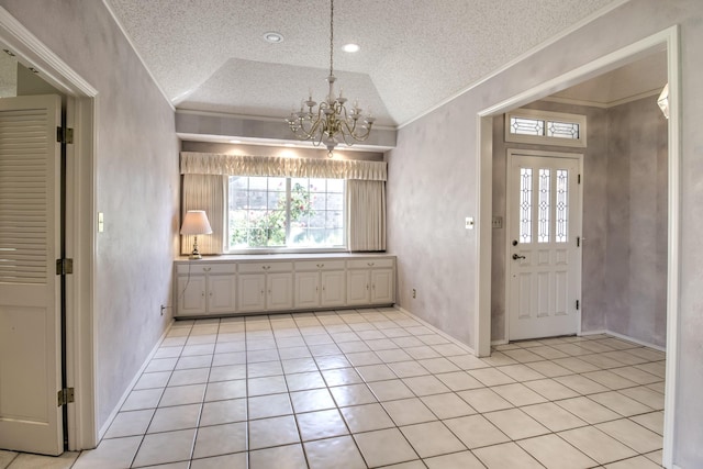 entrance foyer with vaulted ceiling, a textured ceiling, a chandelier, light tile patterned floors, and ornamental molding