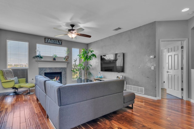 living area with wood finished floors, visible vents, a fireplace, and a ceiling fan