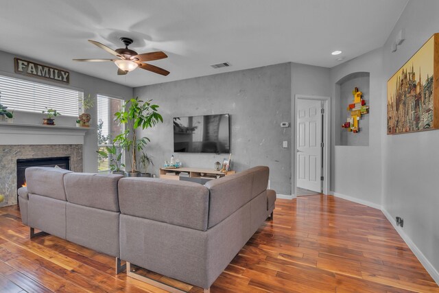 living room featuring a fireplace, visible vents, a ceiling fan, and hardwood / wood-style flooring