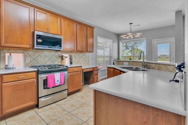 kitchen with stainless steel appliances, light countertops, visible vents, a sink, and tasteful backsplash