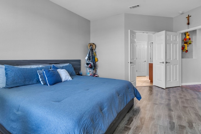 bedroom with baseboards, wood finished floors, and visible vents