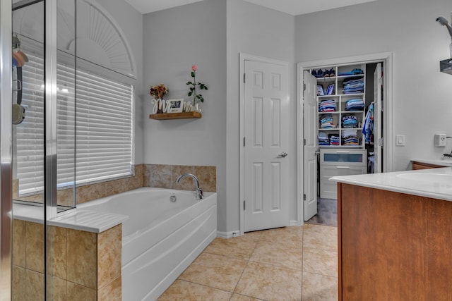 bathroom featuring a bath, vanity, tile patterned flooring, and a walk in closet