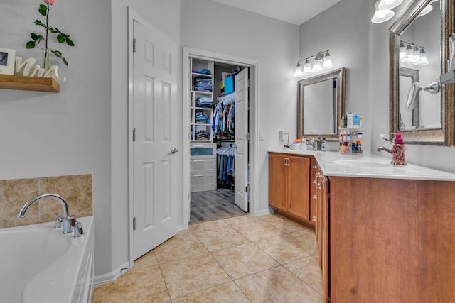 bathroom with tile patterned floors, a sink, double vanity, a spacious closet, and a garden tub