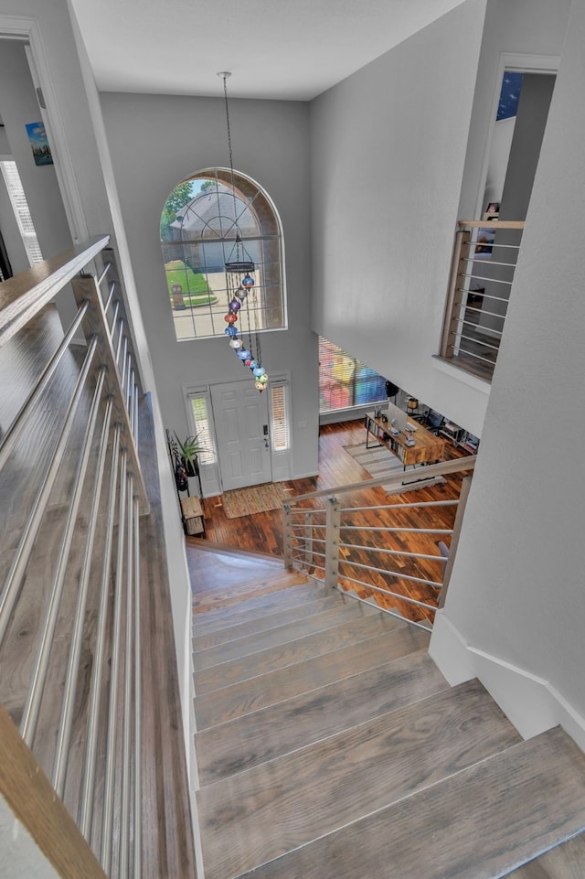 entryway with stairs, a chandelier, wood finished floors, and a high ceiling