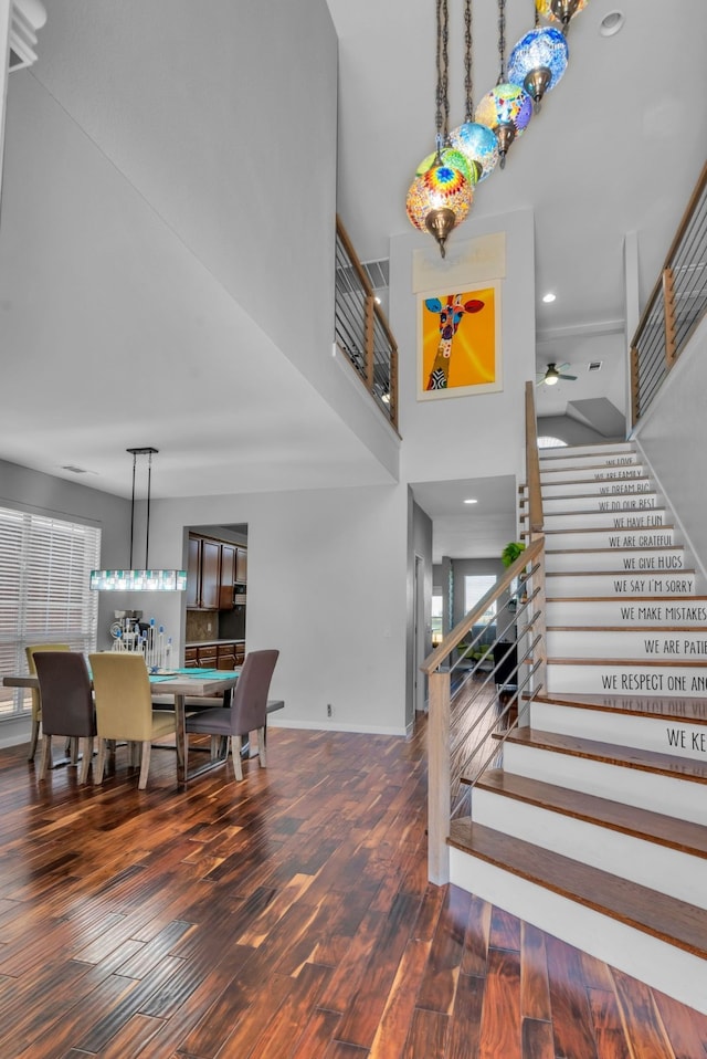 interior space with baseboards, recessed lighting, wood finished floors, a high ceiling, and ceiling fan
