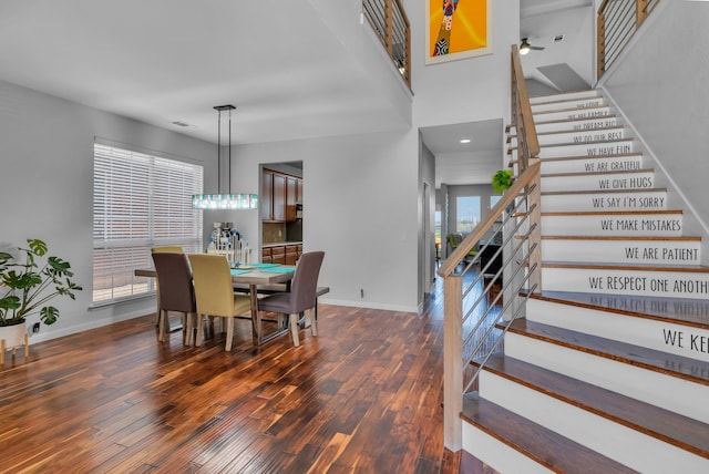 dining room featuring ceiling fan, baseboards, wood finished floors, and stairs