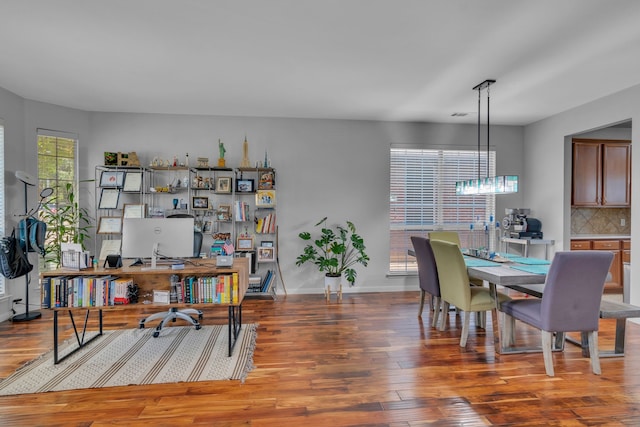 office space with wood finished floors, visible vents, baseboards, and a notable chandelier