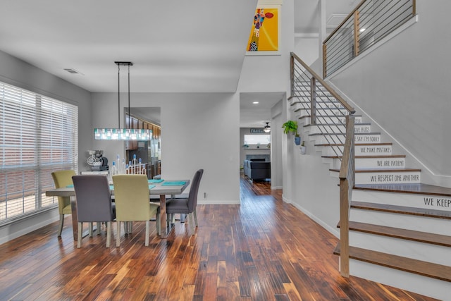 dining area with baseboards, visible vents, stairs, hardwood / wood-style floors, and a fireplace