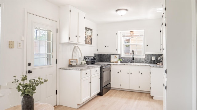 kitchen featuring white cabinets, black range with electric stovetop, light wood finished floors, and backsplash