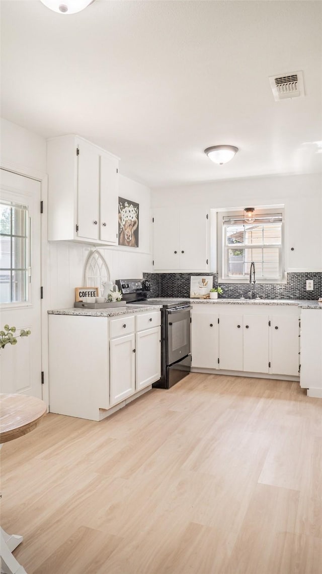 kitchen featuring decorative backsplash, black electric range, visible vents, and plenty of natural light