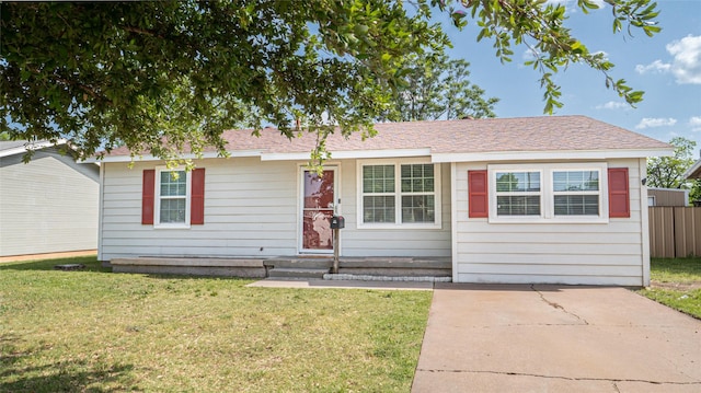 ranch-style house featuring entry steps, a front yard, and fence