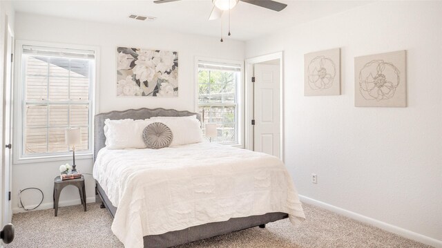 carpeted bedroom with baseboards, a ceiling fan, and visible vents