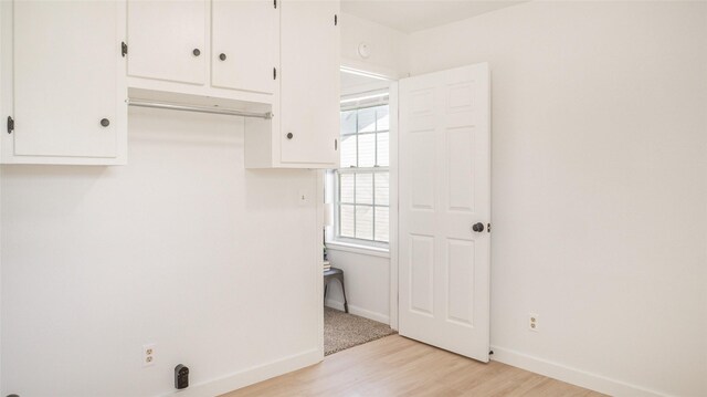 clothes washing area with light wood-style flooring, baseboards, and laundry area