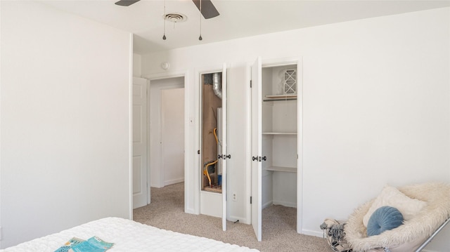 carpeted bedroom featuring visible vents, a ceiling fan, a walk in closet, a closet, and baseboards
