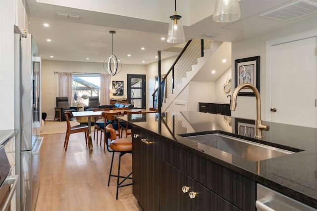 7404 W NW Hwy Unit 9, Dallas, TX 75225 - kitchen with visible vents, light wood-type flooring, a sink, a breakfast bar, and stainless steel appliances