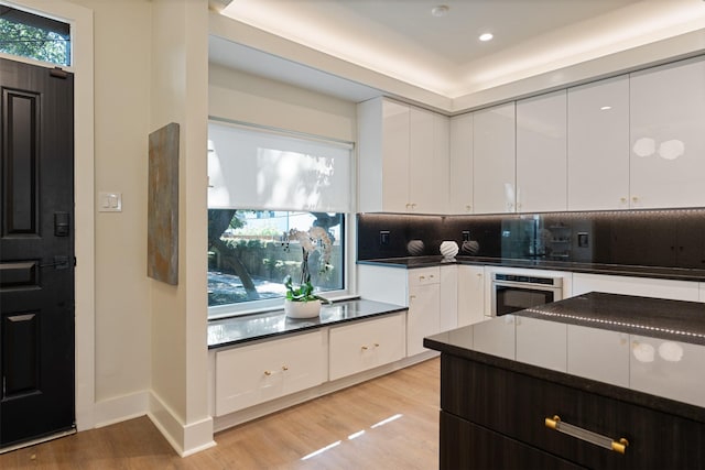 7404 W NW Hwy Unit 9, Dallas, TX 75225 - kitchen featuring dark countertops, light wood-type flooring, white cabinetry, and oven