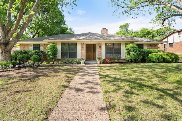 ranch-style home featuring brick siding, a chimney, and a front lawn