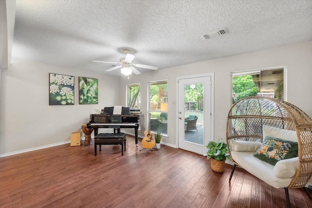 sitting room featuring wood finished floors, visible vents, a ceiling fan, baseboards, and a textured ceiling