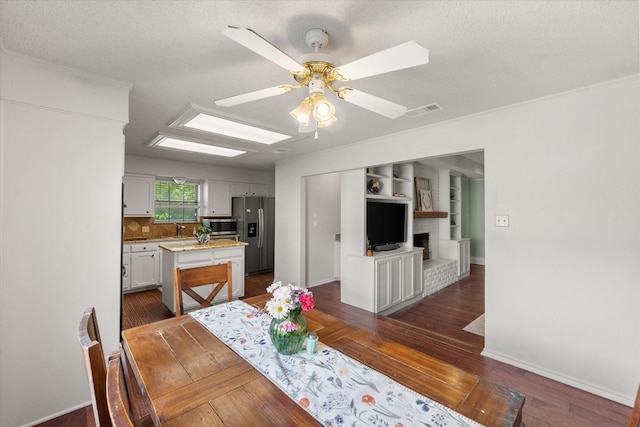 dining room featuring dark wood finished floors, visible vents, baseboards, a textured ceiling, and ceiling fan