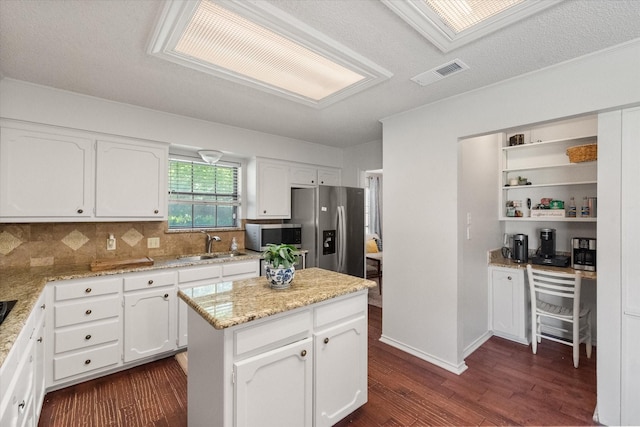 kitchen featuring dark wood-style floors, stainless steel appliances, a sink, tasteful backsplash, and white cabinetry