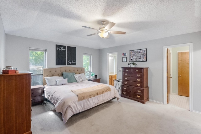 bedroom featuring light carpet, multiple windows, a textured ceiling, and ensuite bathroom
