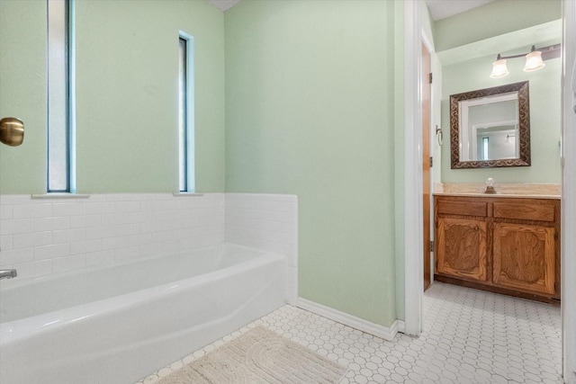 bathroom featuring a garden tub, baseboards, and vanity