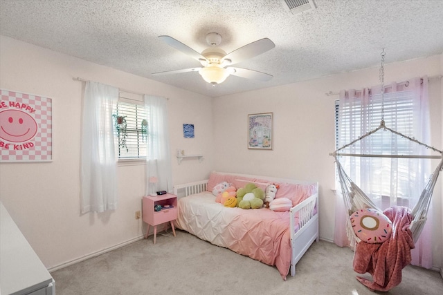 bedroom with light carpet, a ceiling fan, visible vents, and a textured ceiling