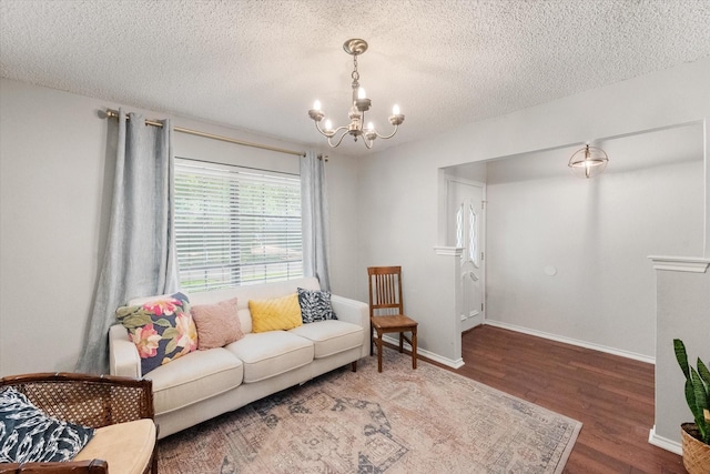 living area featuring an inviting chandelier, wood finished floors, a textured ceiling, and baseboards