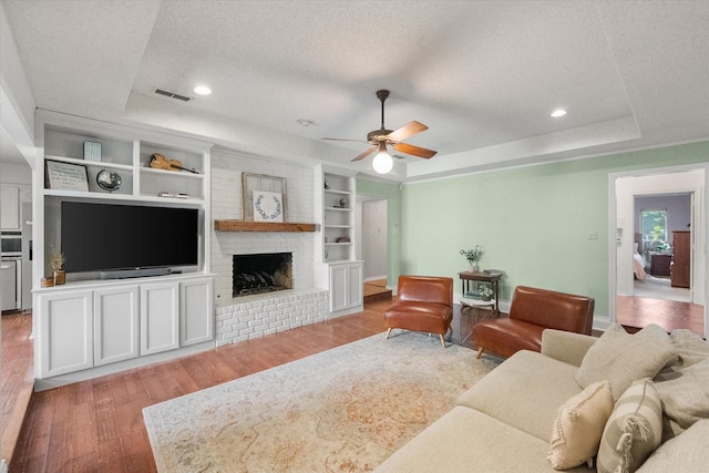 living room with visible vents, wood finished floors, a tray ceiling, and a textured ceiling