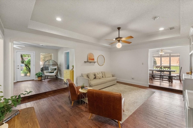 living area featuring plenty of natural light, a tray ceiling, and ceiling fan