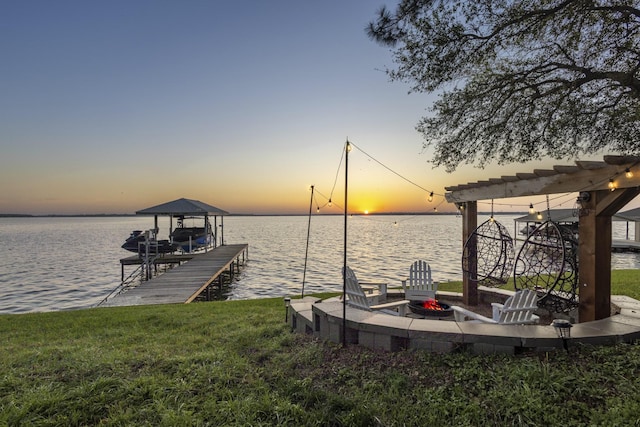 view of dock featuring a yard, an outdoor fire pit, a water view, and boat lift