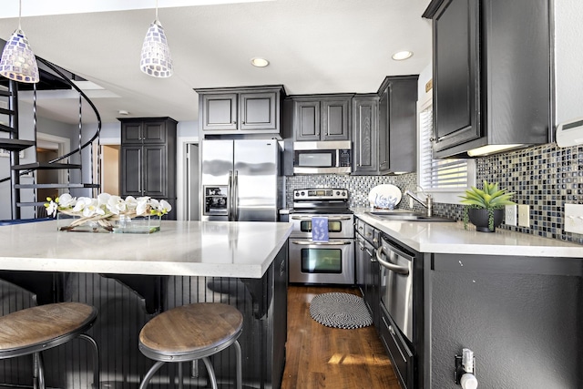 kitchen with dark wood finished floors, light countertops, a sink, tasteful backsplash, and appliances with stainless steel finishes