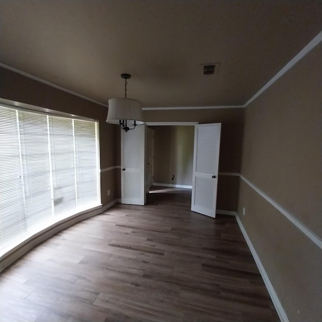unfurnished dining area featuring baseboards, an inviting chandelier, dark wood-type flooring, and ornamental molding