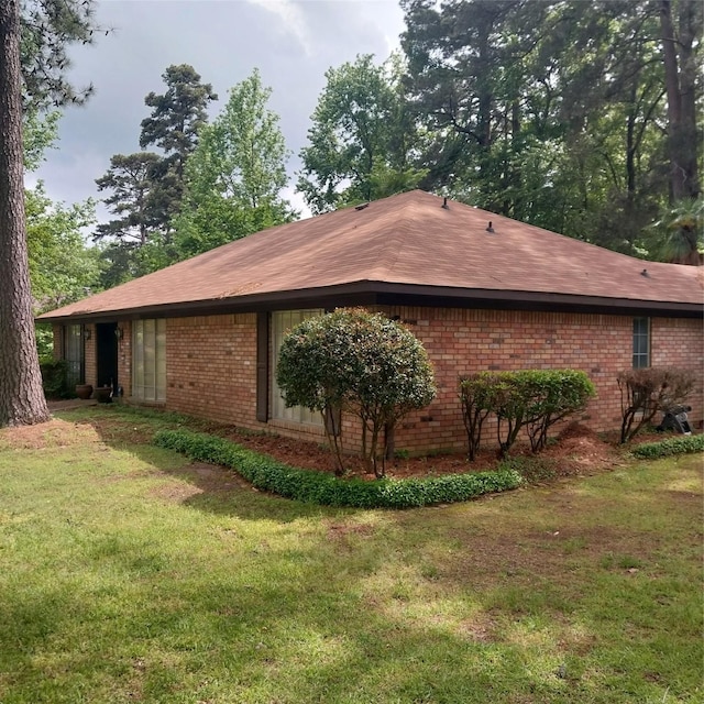 view of property exterior featuring brick siding and a yard