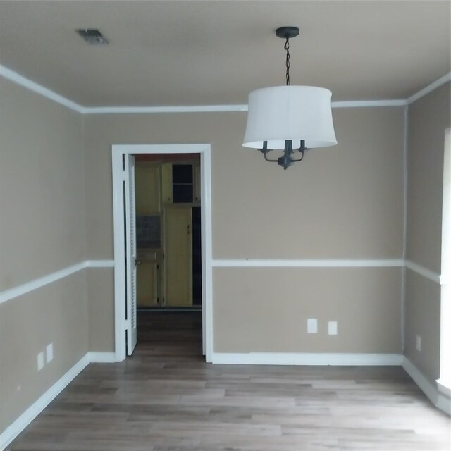 unfurnished dining area with visible vents, baseboards, wood finished floors, and a chandelier