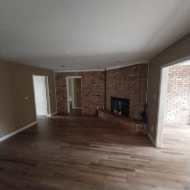 unfurnished living room featuring baseboards, wood finished floors, and a fireplace
