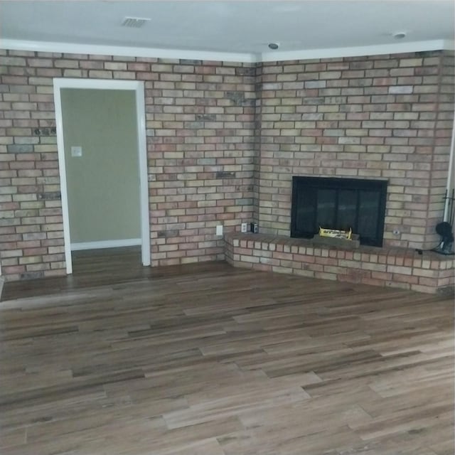 unfurnished living room with wood finished floors, visible vents, and a fireplace