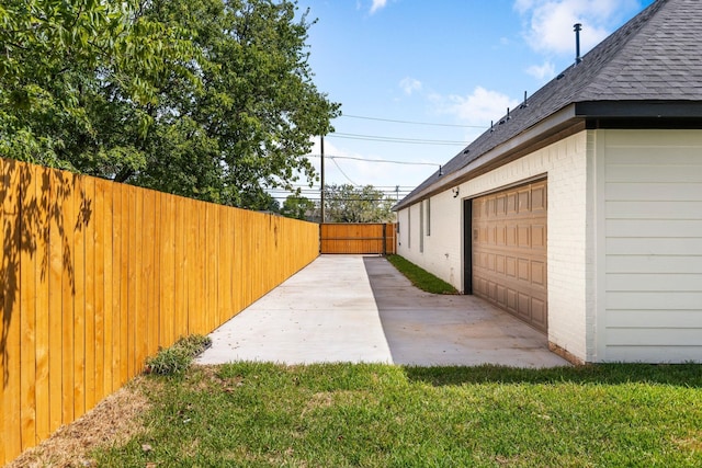 view of side of property with fence, a shingled roof, brick siding, and a yard