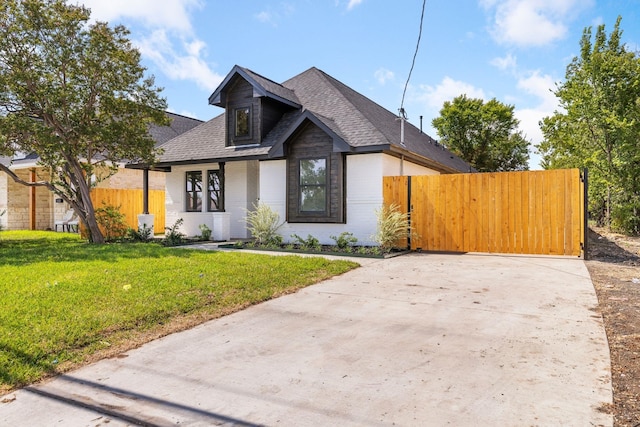 view of front of house featuring fence, driveway, a shingled roof, and a front yard